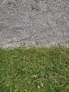 İnce çakıl ve canlı yeşil çimlerden oluşan huzurlu bir bölge, çeşitli doğal dokular ve renkler sergiliyor.