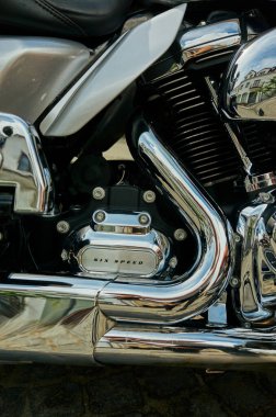 Cilalanmış kruvazör motoru parlayan krom sergileniyor. Sert civata parçaları, yansıtıcı metal yüzeyler, soluk ısı lekeleri, görünür.