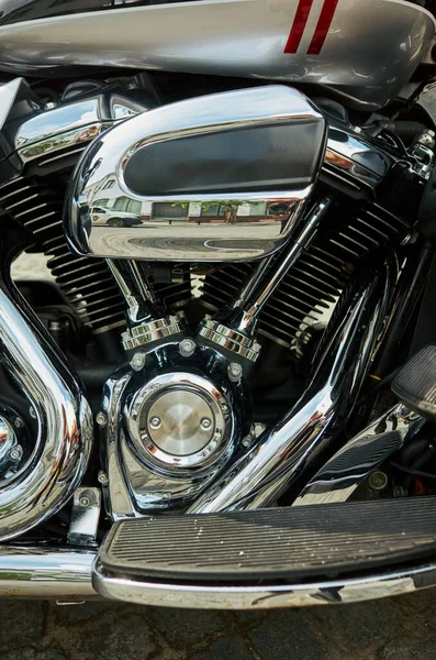 Motosikletli hava temizleyicinin yakın çekimi cilalı kapağı ortaya çıkarıyor. Kırmızı çizgili aksanlar, rozet oyması, yatak tahtası yansıması.,