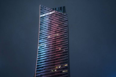 Yağmurun altında yakın cam kule, kıvrımlı cephede dar mahsul LED eğimli, ince yağmur damlaları Varşova, Polonya