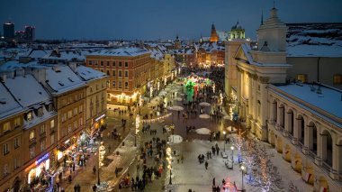 Tatil akşamı için aydınlatılmış tarihi bulvar, kilisenin önünden geçen yayalar ve dekore edilmiş dükkanlar, sıcak Varşova, Polonya
