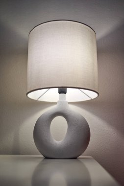 Parlak masaya yakın heykel seramik lamba, kumaş gölgesi dokusu ve kıvrımlı tabanlı, çıtır çıtır bir stüdyo.