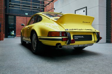 Sarı Porsche, kentsel tuğla avluda, ön ve arka profillerde görünür, parlak boya Varşova, Polonya 24-06-2025