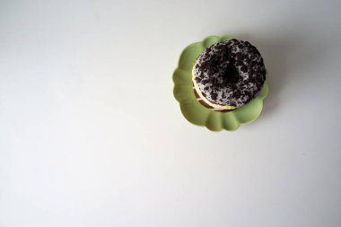 Yığılmış çörekler tabakta asimetrik çörekler yeşil tabakta, merkezden uzak, cömert kompozisyonda.