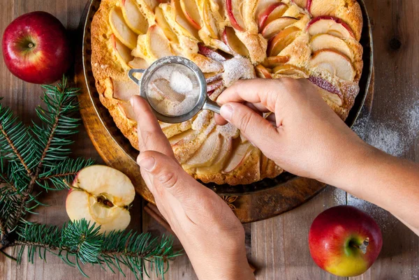 Жінка прикрашає яблучний пиріг цукровою пудрою — стокове фото