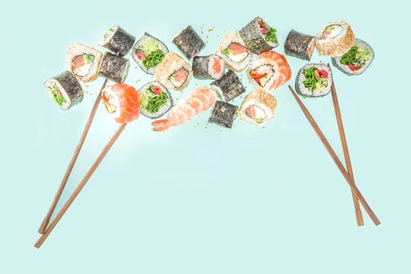 用筷子做的寿司各种味道鲜美的日本寿司 卷片和浅蓝色背景的黑鬼 — 图库照片