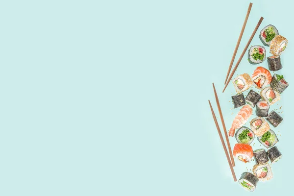用筷子做的寿司各种味道鲜美的日本寿司 卷片和浅蓝色背景的黑鬼 — 图库照片