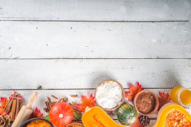 Sonbahar geleneksel pişirme arka planı. Balkabağı turtası, balkabağı baharatı, yarım dilimlenmiş balkabağı, un, kap kacak ve sonbahar dekorasyonu için malzemeler, üst görünüm kopya alanı