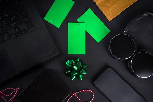 Christmas Clearance and Sale Concept. Black Friday, Green Monday (Cyber Monday) Sale. With Discount Price Tags, Black gadgets and accessories, Shopping Bag. Flat lay top view, black matte background