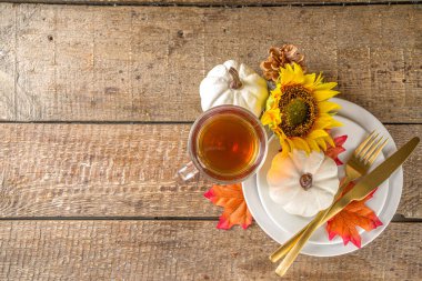 Şükran Günü yemeği konsepti. Tabak, çay fincanı, balkabağı, ayçiçeği ve sıcak ekose ya da süveter, konfor ve rahat tuğla ev arka plan kopyalama alanı ile sonbahar masa ayarı