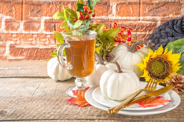 Thanksgiving Food concept. Autumn Table Setting with Plate, Tea cup, pumpkins, Sunflower and Warm Plaid or Sweater, comfort and cozy brick wood home background copy space