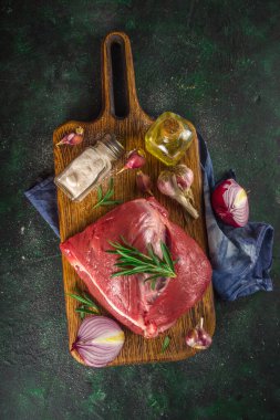 Çiğ et, sığır filetosu, büyük bir dilim dilimleme tahtası ve baharatlar. Siyah yeşil arkaplan, boşluğu kopyala