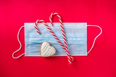 Yüz maskesi ve dekoru olan bir Noel arkaplanı. Mücevherlerle, yüz maskeleriyle, hediyelerle yeni normal Xmas konsepti. Noel yılbaşı konsepti salgın covid-19 sırasında, evde karantinada kalın