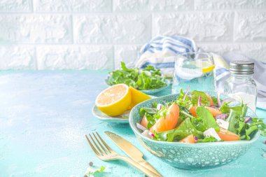 Bir kase sağlıklı sebze salatası, domates, peynir, soğan, zeytin yağı, açık mavi arka plan fotokopi alanı.