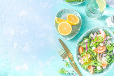 Bir kase sağlıklı sebze salatası, domates, peynir, soğan, zeytin yağı, açık mavi arka plan fotokopi alanı.