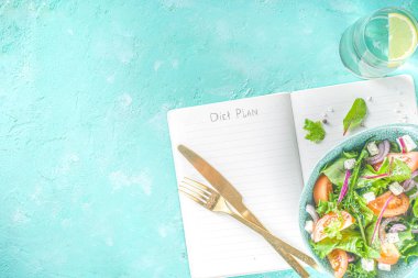 Bir kase sağlıklı sebze salatası, domates, peynir, soğan, zeytin yağı, açık mavi beton arka plan ve diyet planı için not defteri kopyalama alanı.