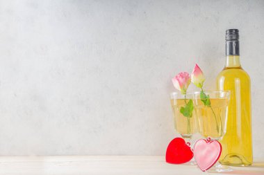 Sevgililer Günü 'nün romantik kutlaması. Kırmızı kalpli ve güllü iki beyaz şarap kadehi. beyaz arkaplan kopyalama alanı