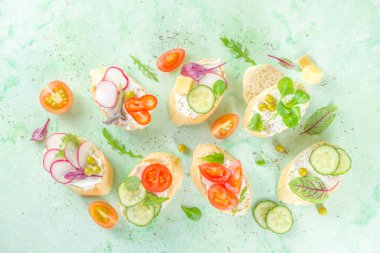 Bahar diyeti sağlıklı gıda geçmişi. Baget ekmekli kahvaltı sandviçi krem peynirli tost ekmeği, çeşitli taze sebzeler. Ya da sağlıklı vejetaryen atıştırmalığı. 