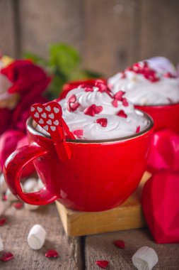 Sevgililer günü sıcak çikolatası ya da kahvesi, iki kırmızı bardak sıcak çikolata ya da sütlü kahve, kremalı şeker kalp parçacıkları, gül buketi hediye paketi.