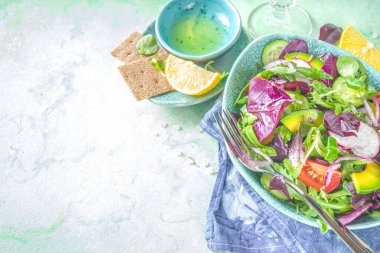 Taze renkli bahar salatası - avokado, taze sebze, salata yaprakları ve peynir, açık yeşil beton arka plan fotokopi alanı