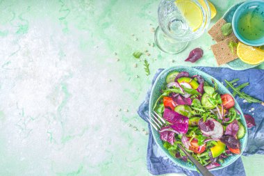 Taze renkli bahar salatası - avokado, taze sebze, salata yaprakları ve peynir, açık yeşil beton arka plan fotokopi alanı