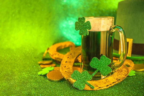 St Patrick\'s Day Pub Bar menu background. Green Beer In Glass with  And with horseshoe, shamrock clover decor, gold coins, on green bokeh glittering background. St Patrick\'s holiday greeting card mock up