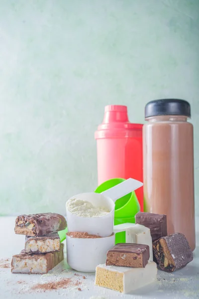 Healthy fit and sport background. Slimming concept. Variety of flavors of protein cocktail powder, ready-made cocktail in bottle and bars on white background.