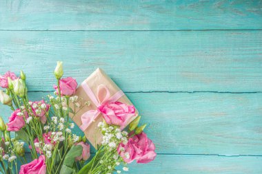 Açık mavi ahşap arka planda güzel bahar çiçekleri. El işi kağıt hediye kutularıyla süslü çiçek kompozisyonu. Sevgililer günü, kadınlar günü, anneler günü tebrik kartı. Üst görünüm düzlüğü