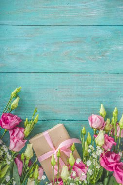 Açık mavi ahşap arka planda güzel bahar çiçekleri. El işi kağıt hediye kutularıyla süslü çiçek kompozisyonu. Sevgililer günü, kadınlar günü, anneler günü tebrik kartı. Üst görünüm düzlüğü