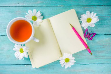 Baharda ya da sonbahar çayının başında bir buket papatya çiçeği ve not defteriyle sıcak bir kahvaltı. Boşluğu kopyala, üst görünüm düzlüğü