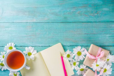 Baharda ya da sonbahar çayının başında bir buket papatya çiçeği ve not defteriyle sıcak bir kahvaltı. Boşluğu kopyala, üst görünüm düzlüğü