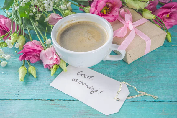 Bouquet of spring, summer flowers, coffee cup and notes good morning, have a nice day on blue wooden table. Summer morning beautiful breakfast, greeting card, top view, flat lay. Mother day concept