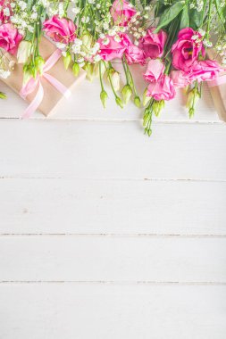Beyaz ahşap arka planda güzel bahar çiçekleri. El işi kağıt hediye kutularıyla süslü çiçek kompozisyonu. Sevgililer günü, kadınlar günü, anneler günü tebrik kartı. Üst görünüm düzlüğü