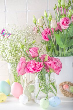 Mutlu Paskalya kutlamaları, davetiye geçmişi. Renkli paskalya yumurtaları ve mavi ahşap masa üzerinde bahar çiçekleri ile bahar çiçekleri kompozisyonu, metin için kopyalama alanı. Düz yatış, üst görünüm.