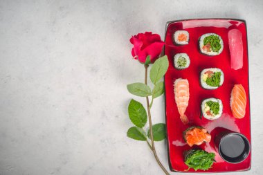 Sevgililer Günü yemeği fikri. Menü, sevgililer günü suşi seti için davetiye, kalp şeklinde dekorasyon ve gül çiçeği buketi. Metin için kopyalama alanı olan üst görünüm