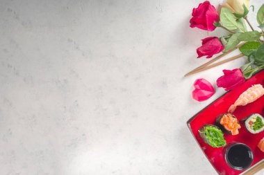 Sevgililer Günü yemeği fikri. Menü, sevgililer günü suşi seti için davetiye, kalp şeklinde dekorasyon ve gül çiçeği buketi. Metin için kopyalama alanı olan üst görünüm