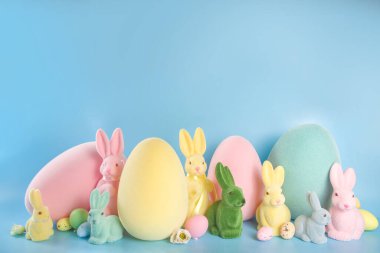 Paskalya Bayramı tebrik kartı, indirim, davetiye geçmişi. Paskalya süsleri geniş sınır pankartı. Renkli Paskalya Yumurtaları ve Tavşancıklar, mavi arka planda bahar çiçekleri kopya alanı.