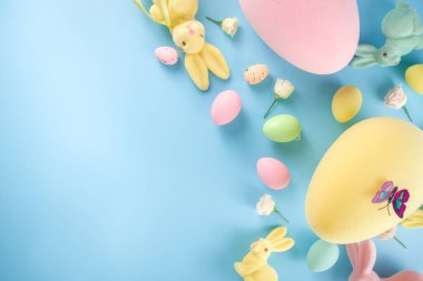 Paskalya Bayramı tebrik kartı, indirim, davetiye geçmişi. Renkli Paskalya Yumurtaları ve Tavşancıklar, mavi arkaplan üzerinde bahar çiçekleri metin alanı için fotokopi alanı ile üst görünüm düz
