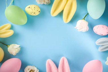 Paskalya Bayramı tebrik kartı, indirim, davetiye geçmişi. Renkli Paskalya Yumurtaları ve Tavşancıklar, mavi arkaplan üzerinde bahar çiçekleri metin alanı için fotokopi alanı ile üst görünüm düz