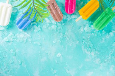 Çok renkli, parlak dondurmalı buzlu dondurma seçimi. Çeşitli dondurmalar, dondurulmuş lolipoplar. Çikolatalı, vanilyalı, böğürtlenli, fıstıklı, portakallı, açık mavi, güneşli arka planda ezilmiş buzlu.