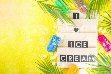 Çok renkli, parlak dondurmalı buzlu dondurma seçimi. Çeşitli dondurma, dondurulmuş lolipoplar. Çikolatalı, vanilyalı, böğürtlenli, fıstıklı, portakallı, trend sarı, güneşli arka planda ezilmiş buzlu.