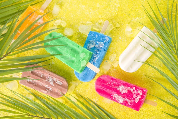 Çok renkli, parlak dondurmalı buzlu dondurma seçimi. Çeşitli dondurma, dondurulmuş lolipoplar. Çikolatalı, vanilyalı, böğürtlenli, fıstıklı, portakallı, trend sarı, güneşli arka planda ezilmiş buzlu.