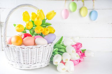 Paskalya yumurtaları ve bahar lale çiçekleriyle dolu bir sepet. Bahar Paskalya Bayramı tebrik kartı, metin için davet arkaplan kopyalama alanı