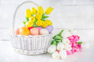 Paskalya yumurtaları ve bahar lale çiçekleriyle dolu bir sepet. Bahar Paskalya Bayramı tebrik kartı, metin için davet arkaplan kopyalama alanı