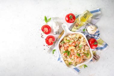 Bahar diyeti sağlıklı vegan makarna. Domatesli İtalyan fusili makarna, yeşil sebzeler, taze otlar, krem peynir veya feta, beyaz masa arkaplan fotokopi alanı