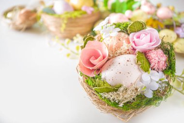 Paskalya tebrik kartı geçmişi. Renkli yumurtalarla, çiçeklerle ve beyaz arkaplandaki yapraklarla bahar ağacı dekorasyon dalları metnin için kopyalama alanı