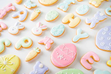 Paskalya kurabiyesi düzeni. Tatlı pastel renkli paskalya şekeri jöleli kurabiyeler, mektuplar, tavşanlar, yumurtalar, diğer semboller. Koyu gölgeler modayı takip eder