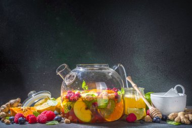 Çaydanlıkta meyve ve çilek çayı. Limonlu, naneli, yabanmersinli, zencefilli, portakallı, elmalı sıcak içecek. Koyu mavi arkaplan fotokopi alanında sıcak aromalı buhar içeceği  