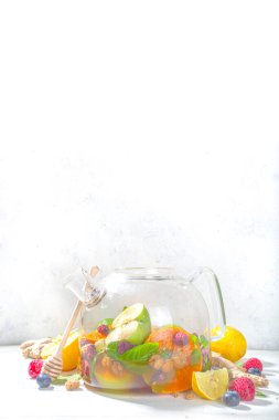 Çaydanlıkta meyve ve çilek çayı. Limonlu, naneli, yabanmersinli, zencefilli, portakallı, elmalı sıcak içecek. Beyaz ahşap arka plan fotokopi alanında sıcak aromalı buhar içeceği  