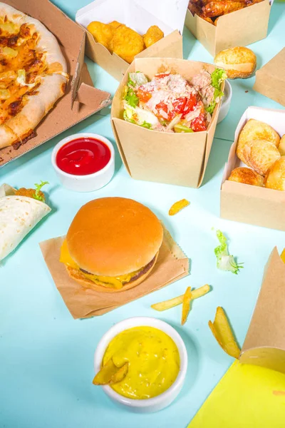 Delivery fastfood ordering food online concept. Large set of assorted take out foods pizza, french fries, fried chicken nuggets, burgers, salads, chicken wings, various sides, white table background